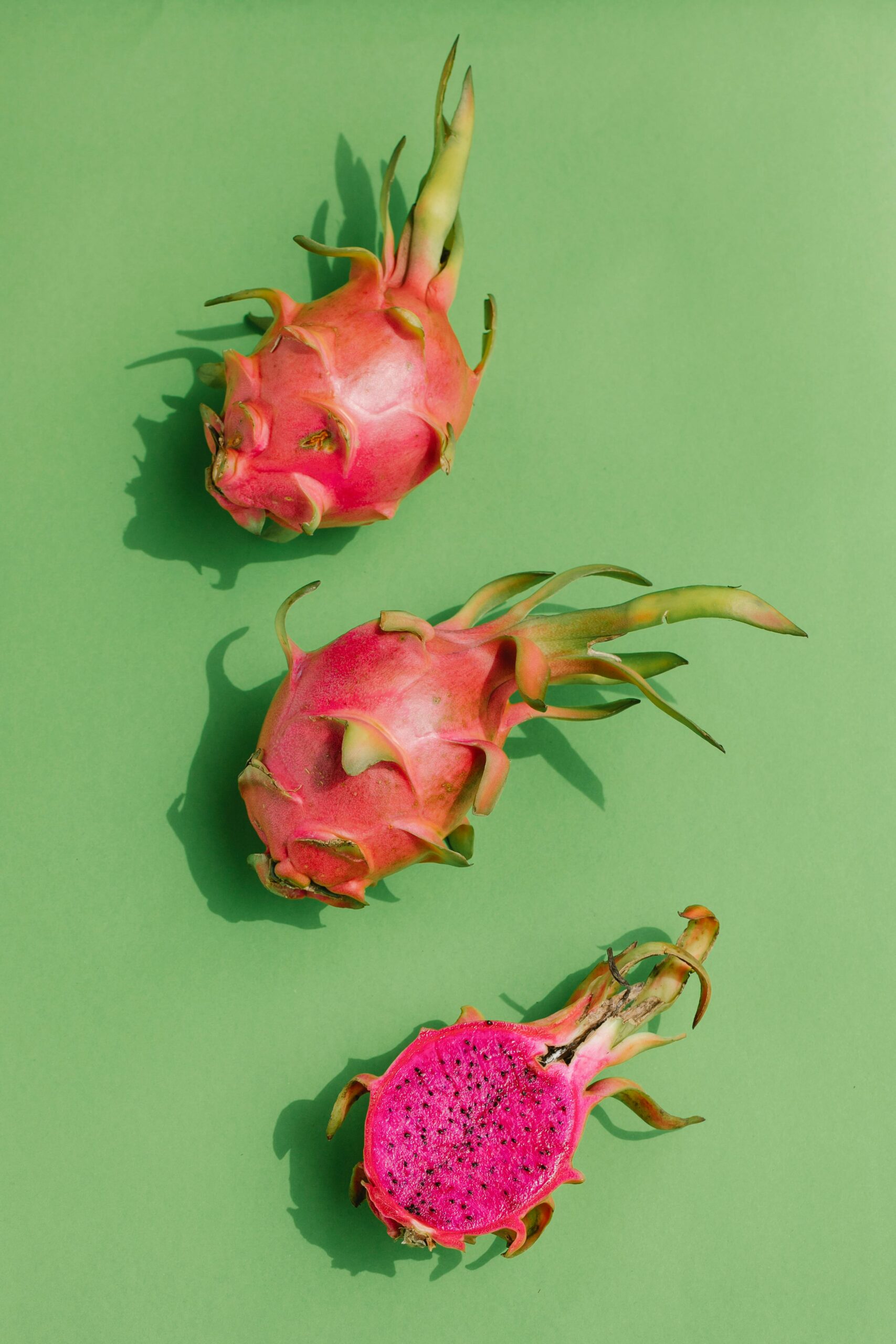 Three dragon fruits on a green backdrop, highlighting tropical freshness.