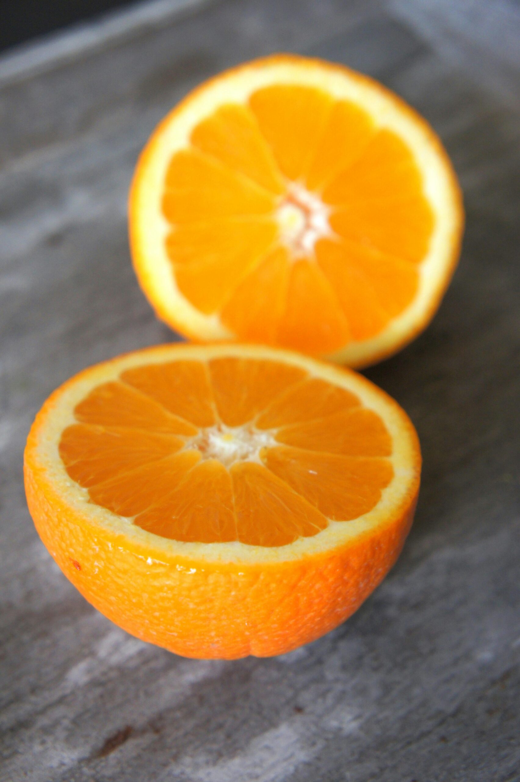 Vibrant close-up of two fresh orange slices on a rustic surface, highlighting their juicy texture.