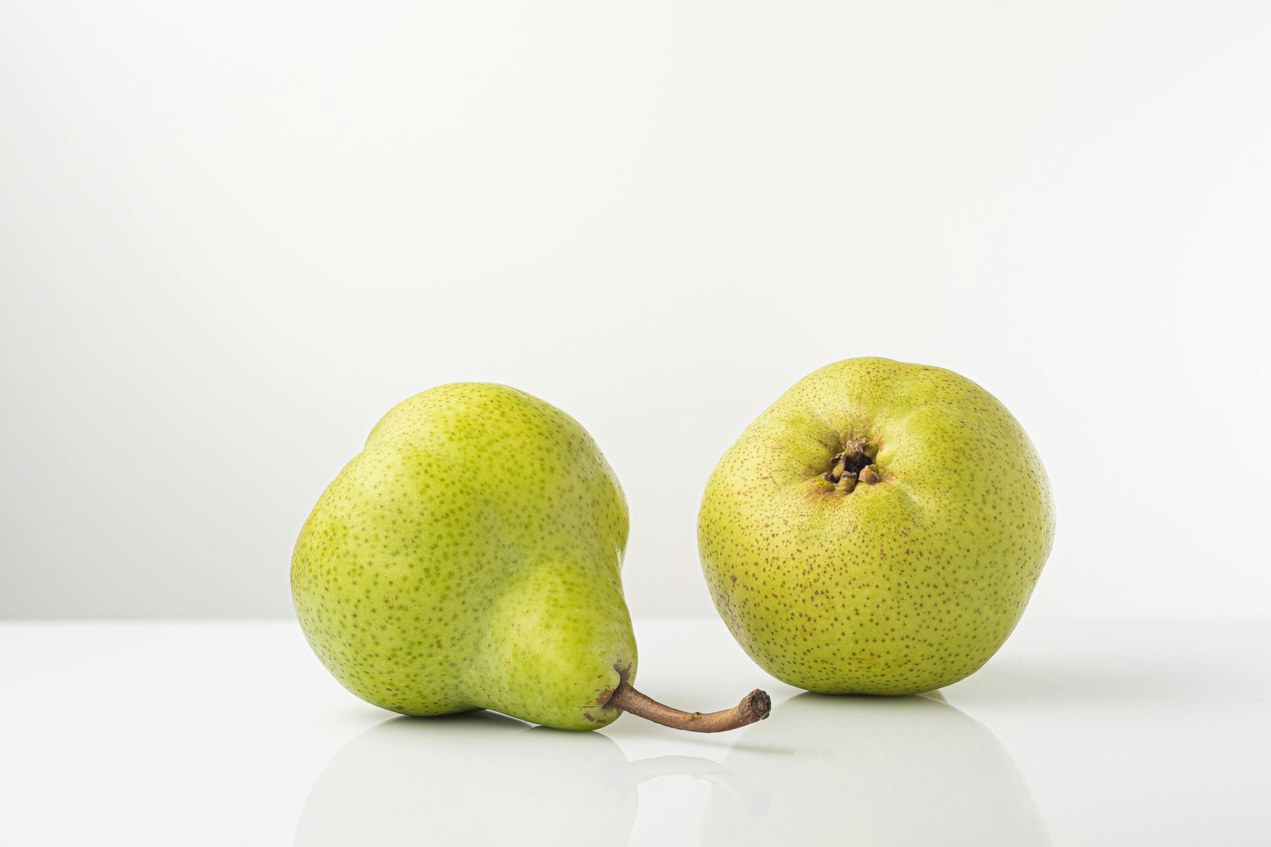 Two ripe pears on a white background, showcasing fresh and healthy produce.